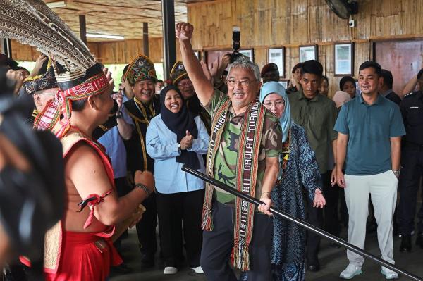 Sultan Abdullah trying the sumpit during a visit to the Kadazandusun Cultural Association Complex (KDCA) and (below) with a baby Bornean elephant known as Taburi at the Orang Utan Co<em></em>nservation Centre in Sepilok in co<em></em>njunction with the Kembara Kenali Borneo programme. With His Majesty is Tunku Azizah. — Bernama