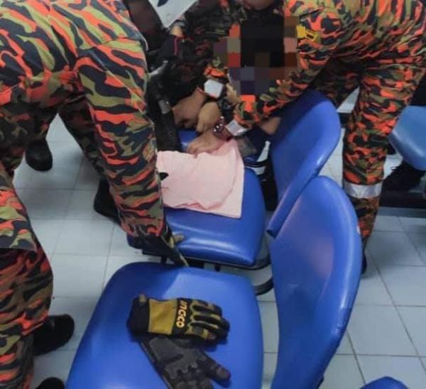 Firemen using a hydraulic equipment to free the five-year-old girl whose leg was stuck between the seats of a link chair at the Jemaluang health clinic in Mersing. 