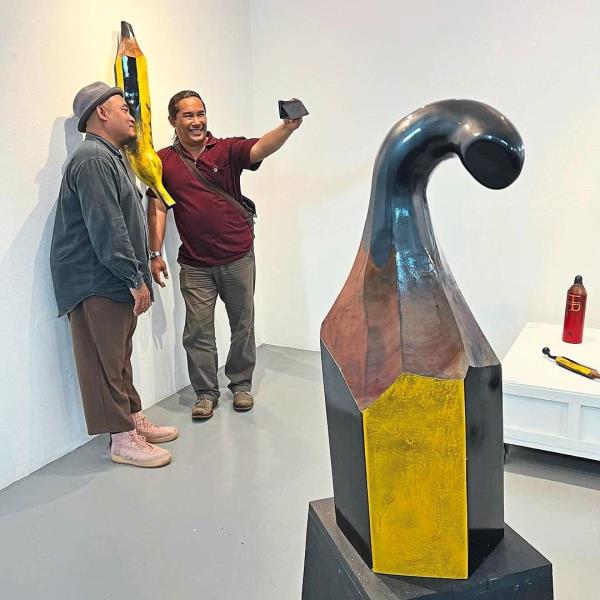 Visitors taking a photograph at Daud’s exhibition, with the sculpture 'My Pencil' seen in the foreground. Photo: Handout