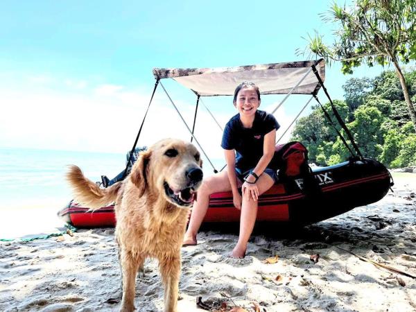 A lass and her old golden retriever happily landing at Mo<em></em>nkey Beach, Penang, on their inflatable raft.