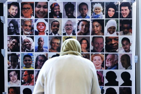 View from behind of a woman in a headscarf looking at a wall of photos of victims