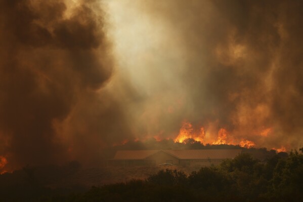 The Airport Fire burns over a structure Tuesday, Sept. 10, 2024, in El Cariso, an unincorporated community in Riverside County, Calif. (AP Photo/Eric Thayer)