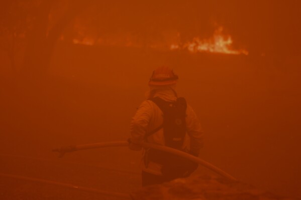 A firefighter battles the advancing Airport Fire Tuesday, Sept. 10, 2024, in unincorporated Riverside County, Calif. (AP Photo/Etienne Laurent)